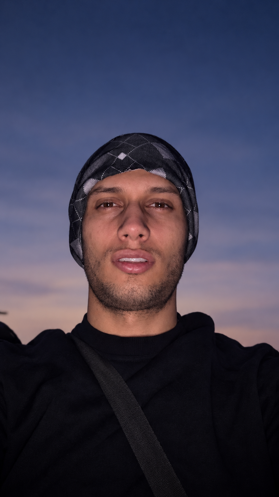 An evening portrait of Hamid Ghanbari wearing a patterned head wrap